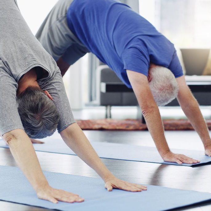 Two men in their fifties doing yoga downward dog pose